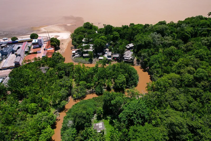 Vue aérienne de l'embouchure de la rivière Paxicu au bout de la Praia da Fazendinha, avec des maisons dans la forêt et l'Amazone derrière.
