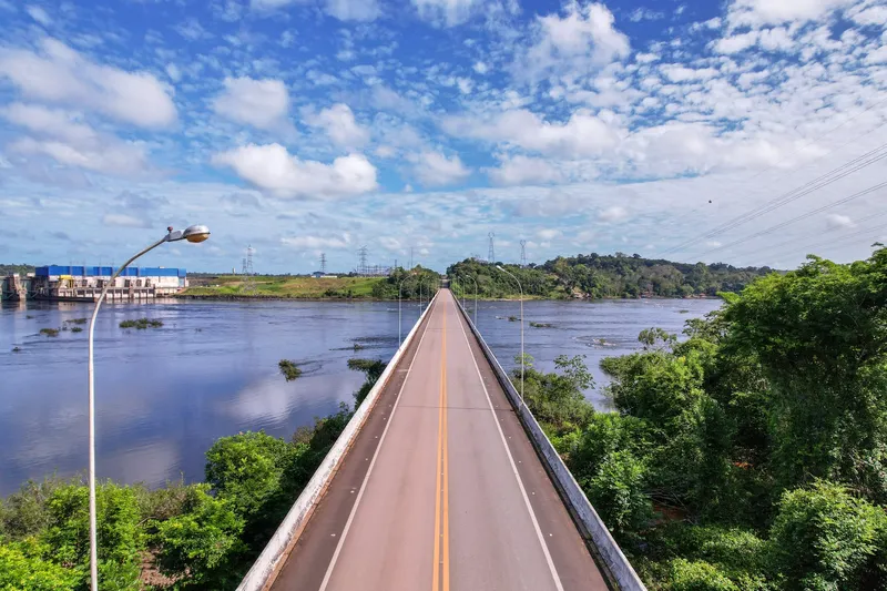 Deck of Ponte Tancredo Neves seen from above, with yellow center line, lampposts and the river on both sides