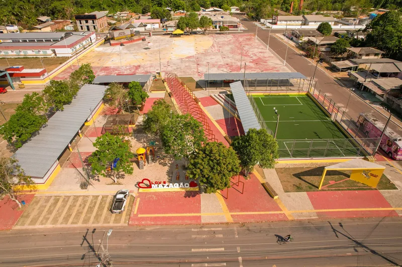Aerial view of the Mazagão Novo square, with an artificial turf pitch, playground, trees, a Love Mazagão sign and courts behind.