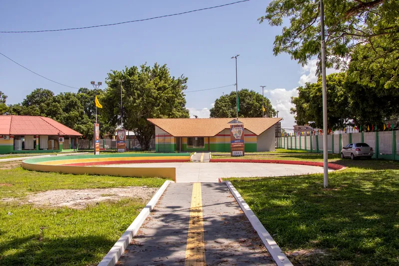 Caminho com piso tátil até o anfiteatro circular do Centro de Cultura Negra do Amapá, com prédios coloridos e árvores.