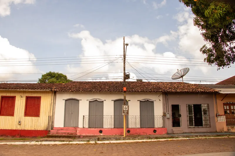 Fileira de casas antigas em Mazagão Velho, com telhados de cerâmica, portas altas em arco e fachadas coloridas, vista de frente.