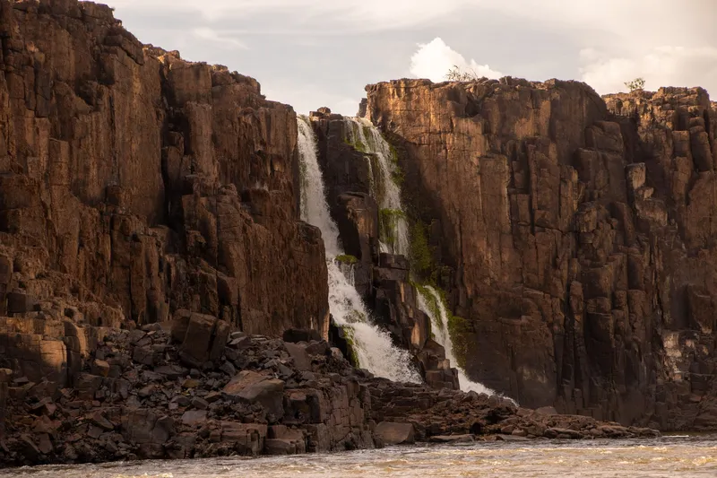 Paredones de roca oscura con caídas de agua estrechas en la Cachoeira de Santo Antônio, con luz de tarde