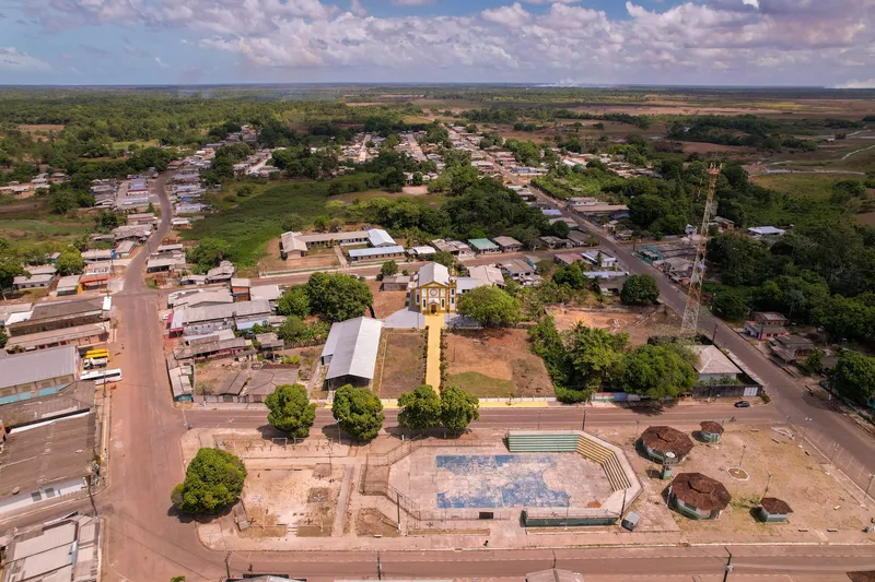 Vista aérea ampla da cidade de Amapá com a Igreja Nossa Senhora de Nazaré ao centro, uma praça com quadra à frente e o campo ao horizonte