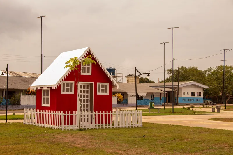 Casinha vermelha decorativa com cerca branca no gramado da Praça de Itaubal do Piririm