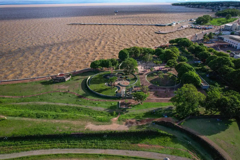 Vue aérienne du Parque do Forte : pelouses, places circulaires et arbres au bord de l'Amazone aux eaux boueuses, avec des jetées au fond.