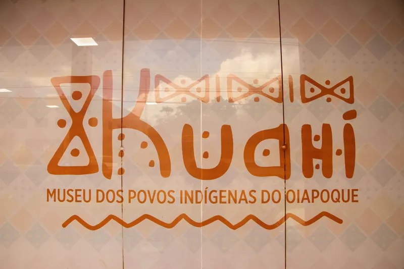 Logotipo del Kuahí, Museo de los Pueblos Indígenas de Oiapoque, pintado en tono terracota con grafismos indígenas en el vidrio de la entrada