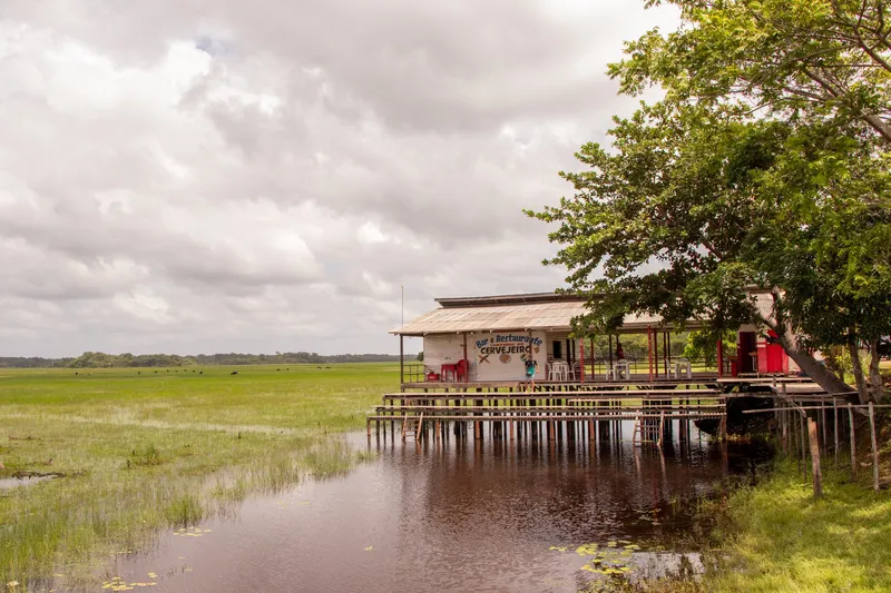 Restaurante sobre pilotes al borde del campo inundable de la APA do Rio Curiaú, bajo cielo nublado