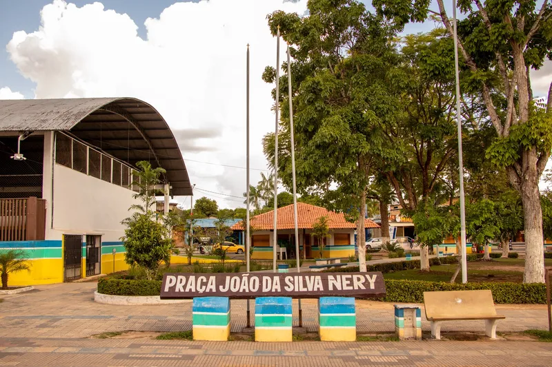 Praça João da Silva Nery sign with trees, an orange-roofed kiosk and a covered sports hall