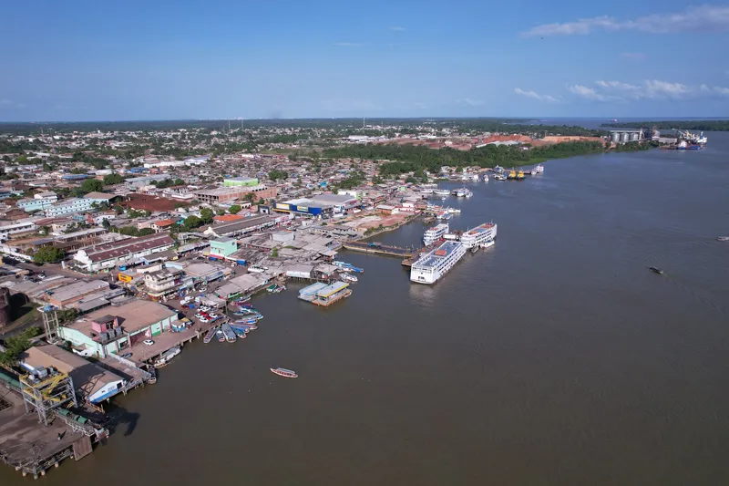 Vista aérea de la orilla de Santana con barcos de pasajeros atracados, casas junto al río y la terminal portuaria al fondo.