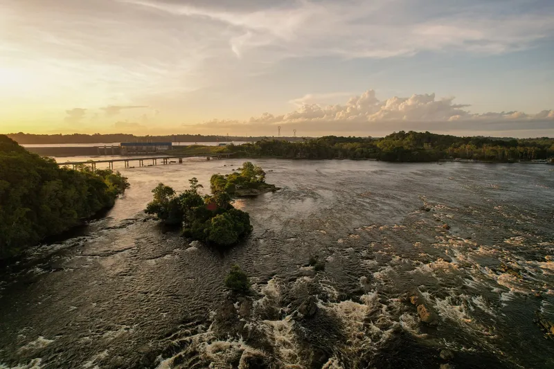 Aerial sunset view of river rapids with small wooded islets and Ponte Tancredo Neves in the background