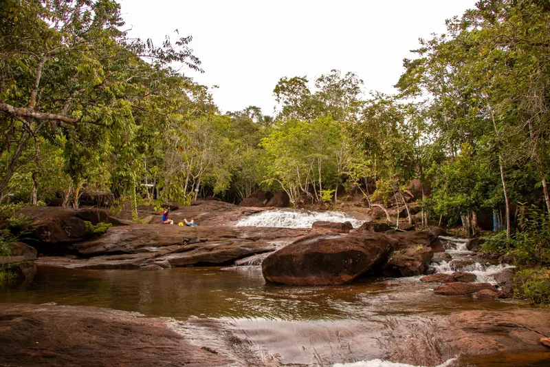 Cachoeira do Traíra: small waterfall over rock slabs, a dark-water pool and surrounding forest