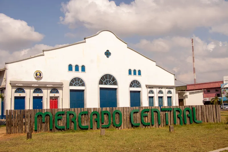 Facade of the Mercado Central de Macapá with blue doors, behind a wooden fence bearing the market's name in green letters.
