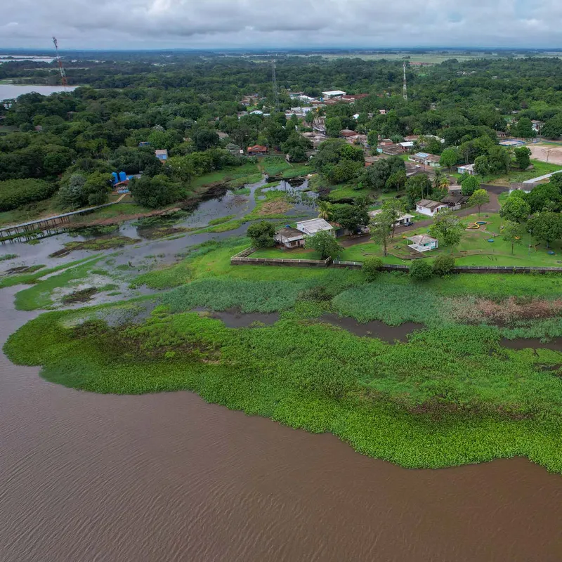 Vista aérea da orla de Pracuúba, com vegetação aquática, praça, casas e passarela.