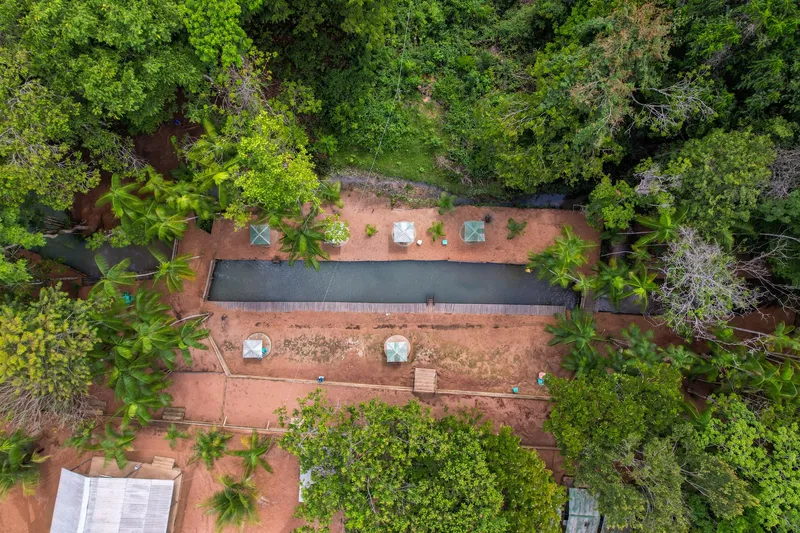 Vista aérea de cima do Balneário Pé da Serra: piscina natural retangular, quiosques e mata em volta