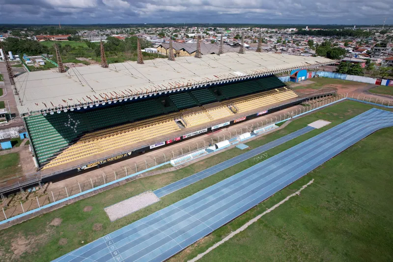 Vista aérea en diagonal de la tribuna del Estádio Zerão y la pista azul, con barrios de Macapá al fondo.