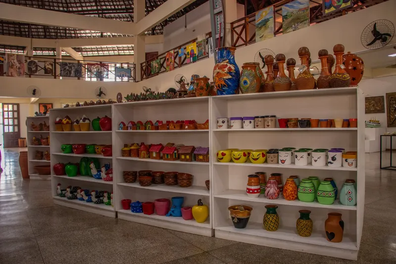 White shelves with brightly painted ceramic vases and pieces at Casa do Artesão Amapaense.