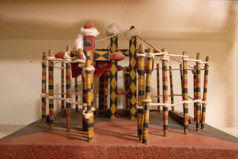 Maqueta de madera pintada de amarillo, negro y rojo, con estacas atadas con cuerdas, expuesta en el Museo Kuahí