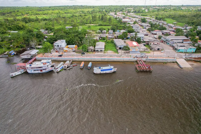 Vue aérienne du front de rivière de Cutias do Araguari : bateaux amarrés le long du mur de quai, large fleuve au premier plan et ville au fond