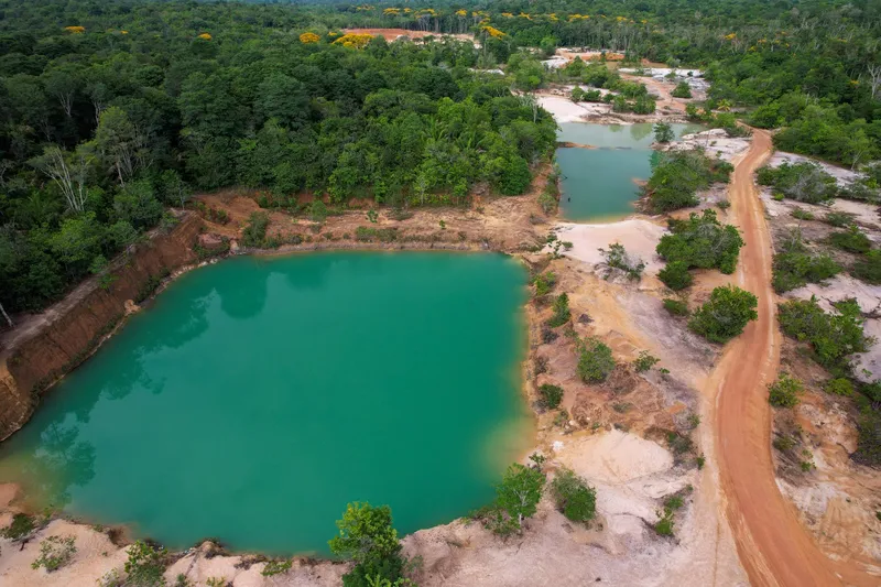 Aerial view of Barranco do Geraldão: emerald-green lakes between earth banks, a dirt road and surrounding forest