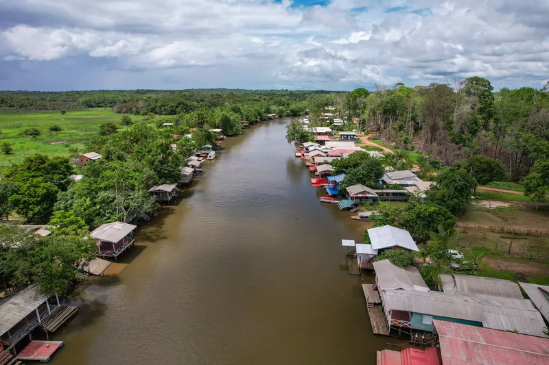 Aerial view of the river through the Ariri community, with stilt houses on both banks and forest stretching to the horizon.