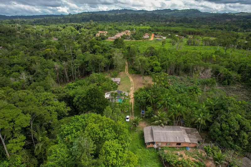 Vista aérea de la comunidad del Balneário da Dona Antônia: camino de tierra, casas entre palmeras y selva hasta las sierras.