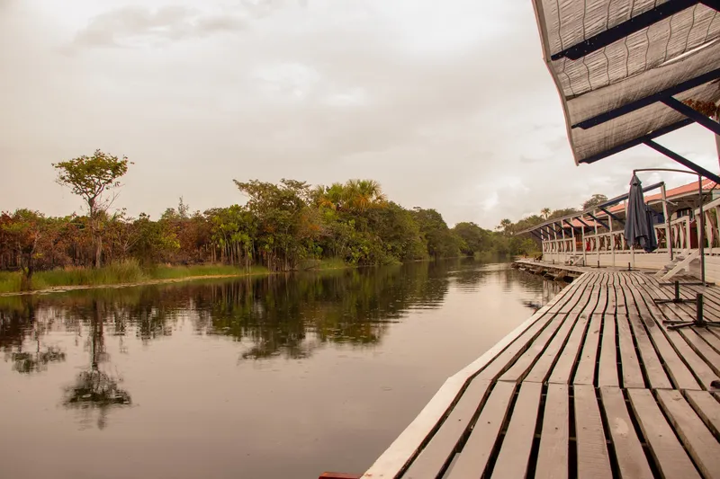 Calm river reflecting the forest, seen from the wooden deck of Paraíso da Sereia on a cloudy day