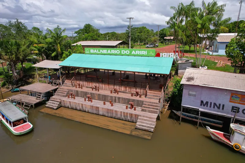 Aerial view of the covered deck with green roof and Balneário do Ariri sign, with wooden tiers stepping down to the river.