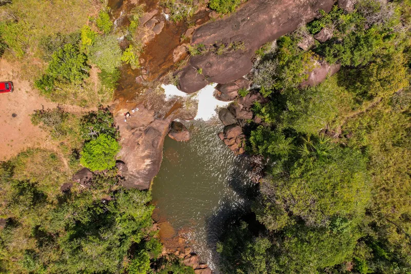Vista aérea cenital de la Cachoeira do Pium: caída de agua entre grandes rocas que forma una poza, rodeada de vegetación verde