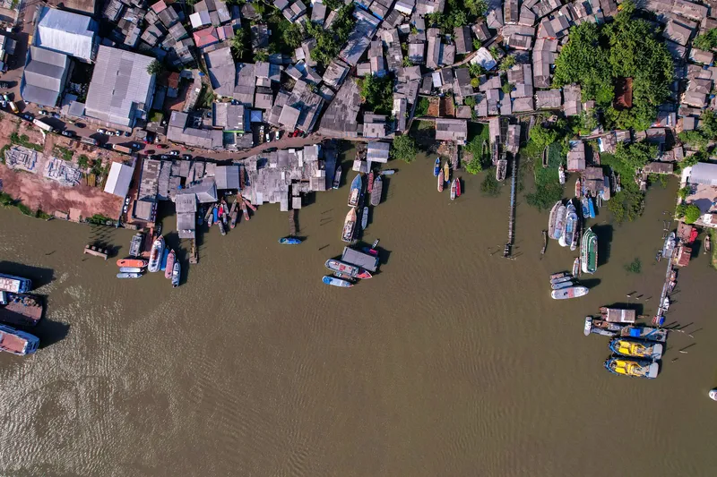 Vista aérea cenital de la ribera de Santana: casas sobre pilotes, muelles de madera y decenas de barcos atracados en agua turbia.