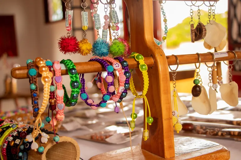 Beaded bracelets, keychains and handmade pendants hanging on a wooden display at Casa do Artesão de Mazagão.